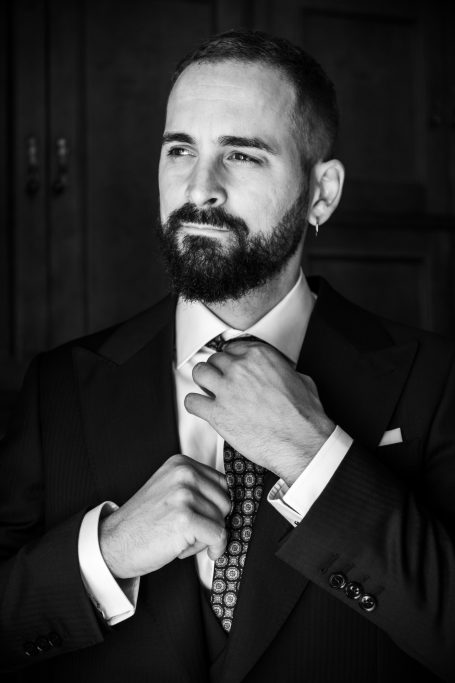 Manuel ajustándose la corbata, mirando por la ventana. Boda en Hacienda Torrequemada, sevilla