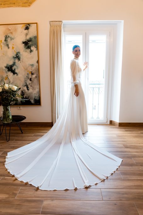Carla luce un vestido de novia precioso ante la ventana de su casa, en castilleja de la cuesta. sevilla