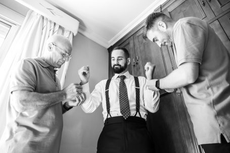 Manuel sonriente mientras su padre y hermano le ponen los gemelos. Boda en Sevilla, Hacienda Torrequemada.