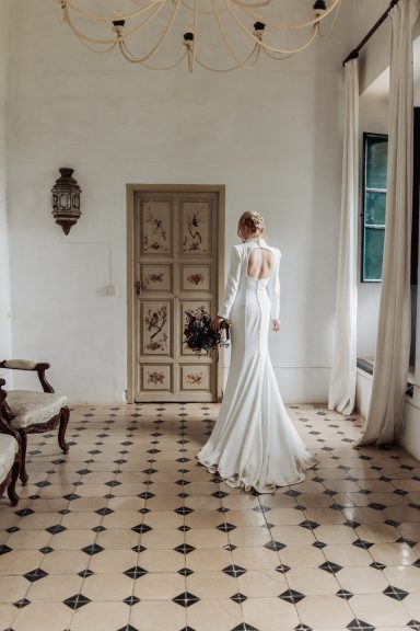 Mujer de espaldas con vestido de novia en un interior elegante y luminoso.