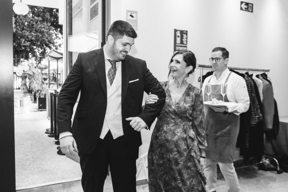 Pareja elegante caminando juntos en un evento, sonrientes y bien vestidos.